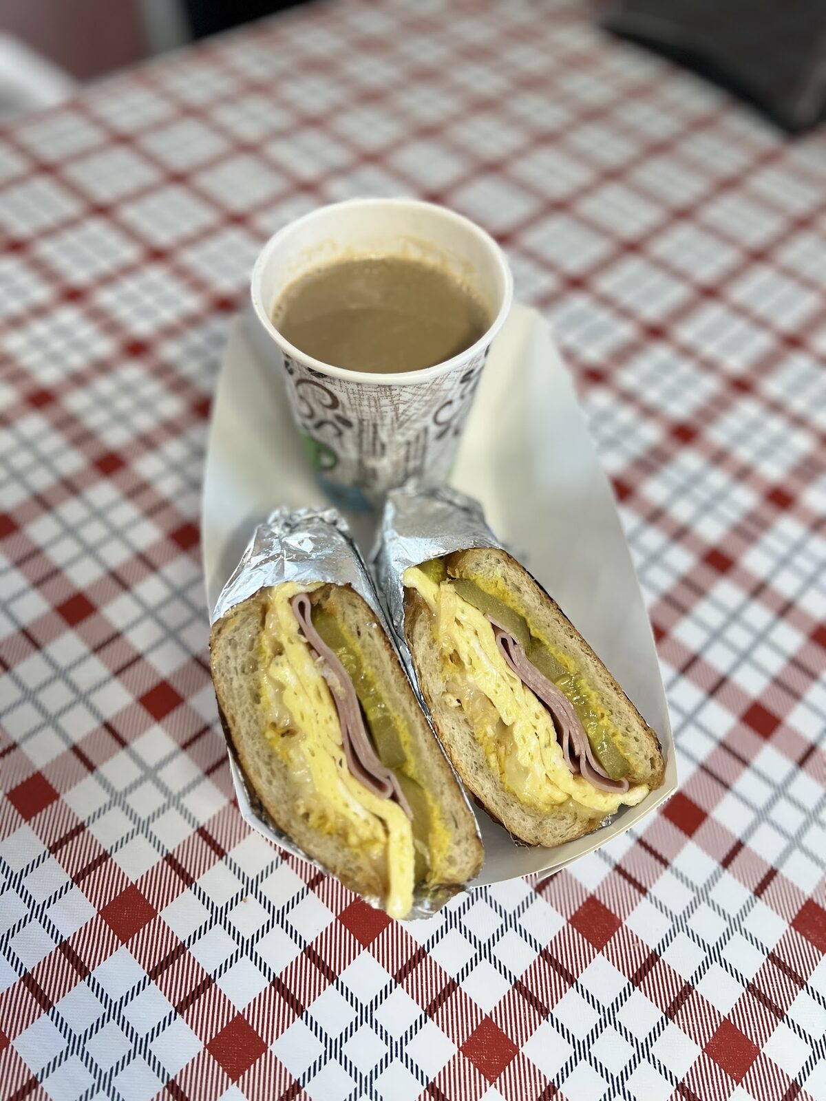 Breakfast sandwich with café con leche on a checkered tablecloth